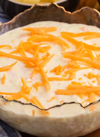 Pineapple salad topped with shredded cheddar cheese, served in a decorative glass bowl.
