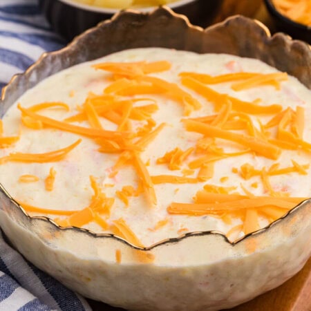 Pineapple salad topped with shredded cheddar cheese, served in a decorative glass bowl.