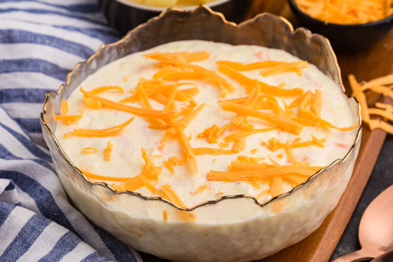 Pineapple salad topped with shredded cheddar cheese, served in a decorative glass bowl.