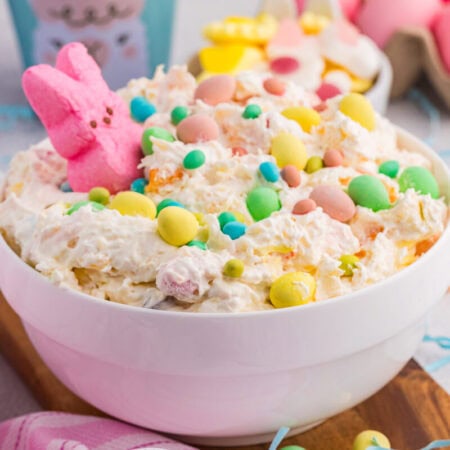 Easter dessert bowl with creamy fluff, pastel candies, marshmallow bunny, and dyed eggs background.