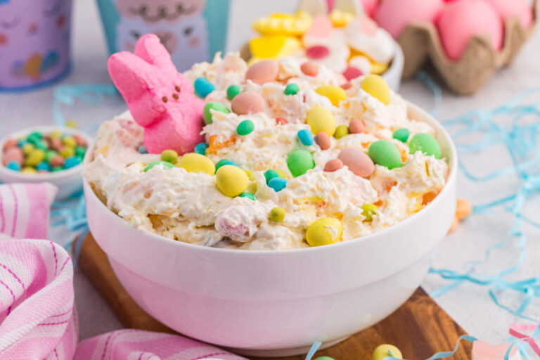 Easter dessert bowl with creamy fluff, pastel candies, marshmallow bunny, and dyed eggs background.