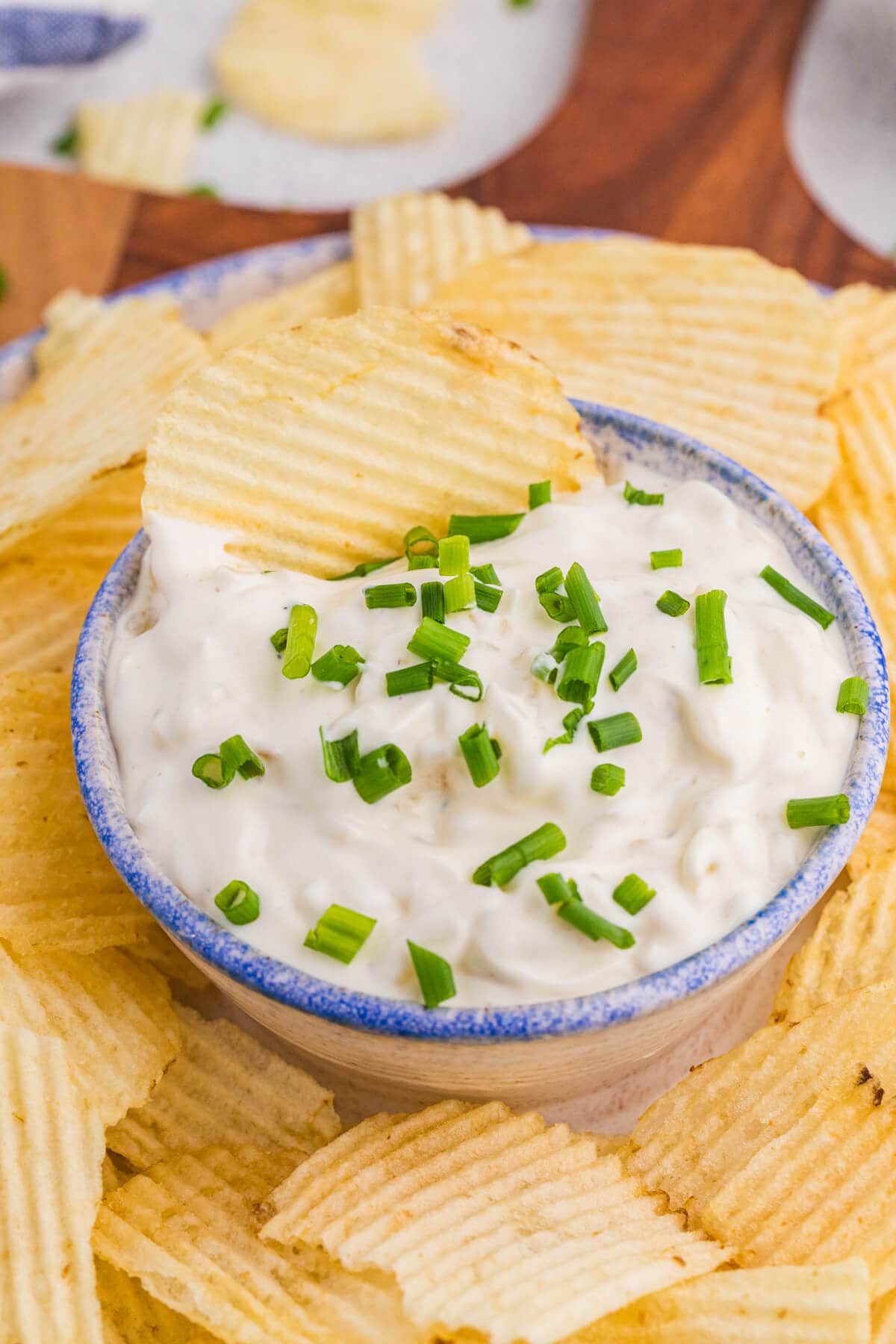 Macro creamy onion dip with chopped chives and crispy ridged chips.