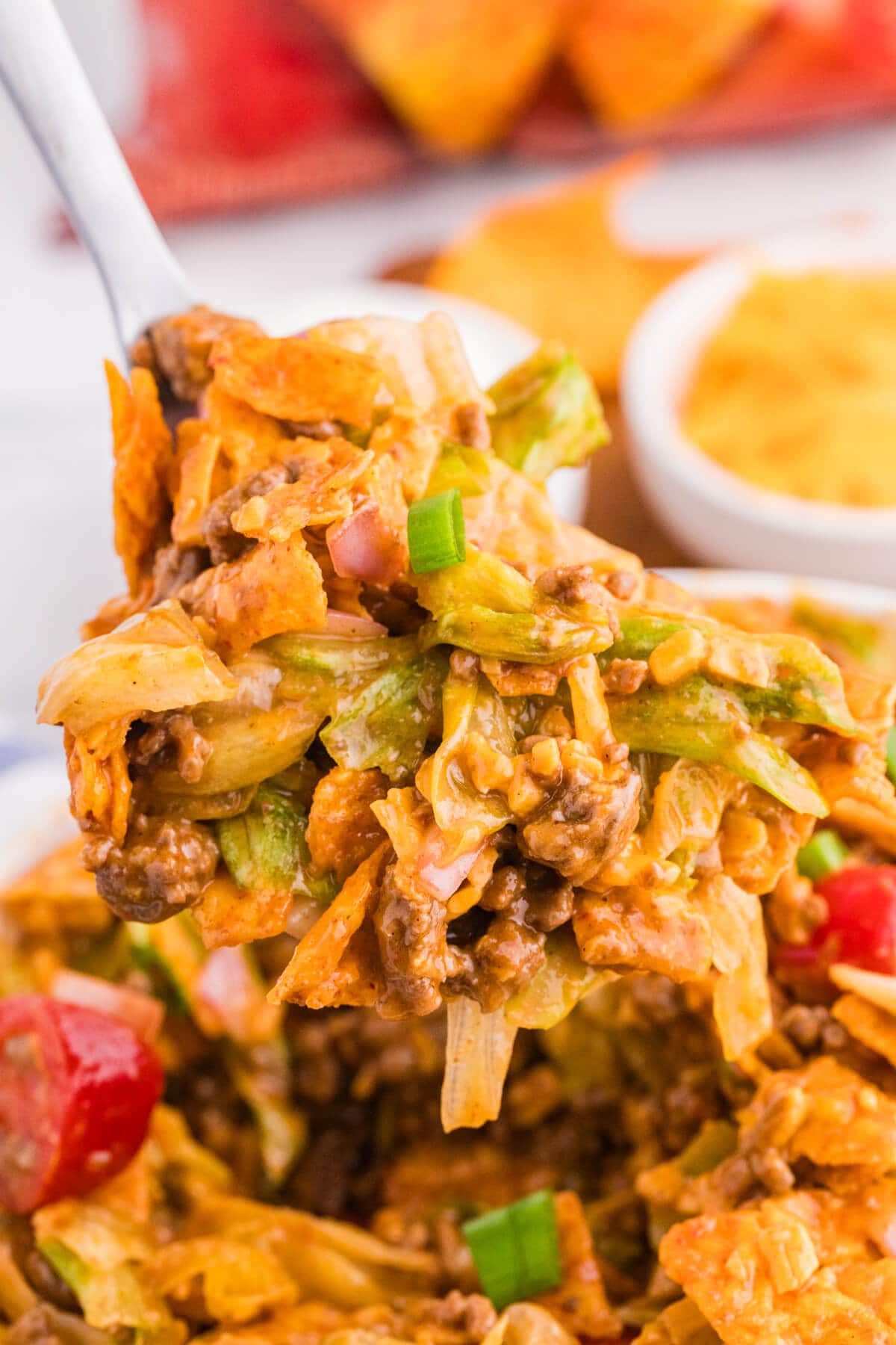 Spoonful of Dorito Taco Salad with seasoned ground beef, lettuce, cheddar cheese, red onion, green onions, and crushed nacho cheese Doritos.