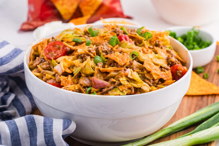 Bowl of Dorito Taco Salad with seasoned ground beef, lettuce, tomatoes, red onion, cheddar cheese, green onions, and crushed nacho cheese Doritos.