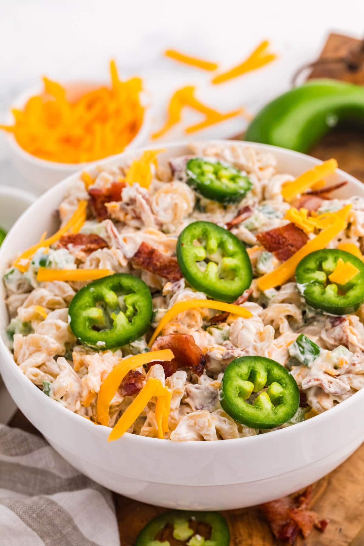 Close-up of creamy Jalapeño Popper Pasta Salad topped with fresh jalapeño slices, shredded cheddar cheese, and crispy bacon.