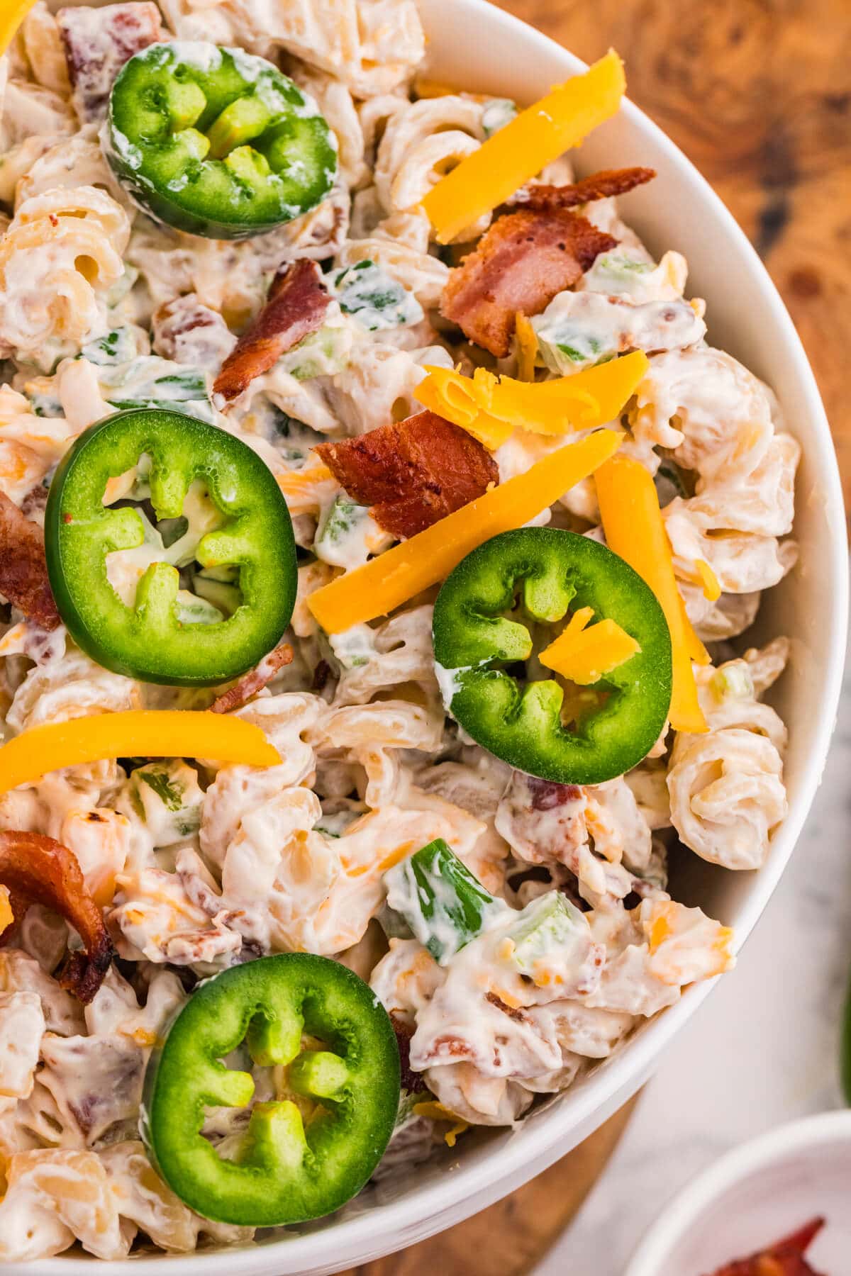 Close-up of creamy Jalapeño Popper Pasta Salad with rotini, bacon, cheddar cheese, green onions, and fresh jalapeño slices.