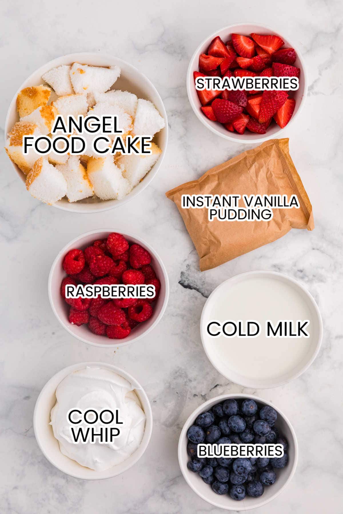 Ingredients for Angel Food Cake Trifle including cubed angel food cake, strawberries, raspberries, blueberries, instant vanilla pudding, cold milk, and Cool Whip.