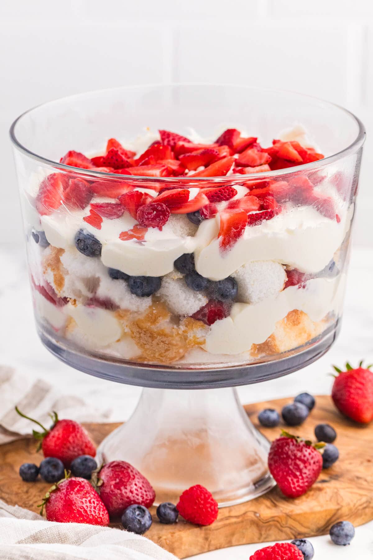Angel Food Cake Trifle layered with creamy vanilla filling, strawberries, blueberries, and raspberries in a glass trifle bowl.