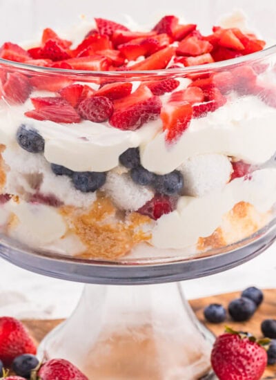 Angel Food Cake Trifle layered with fluffy cake, creamy vanilla filling, strawberries, blueberries, and raspberries in a clear glass trifle bowl.