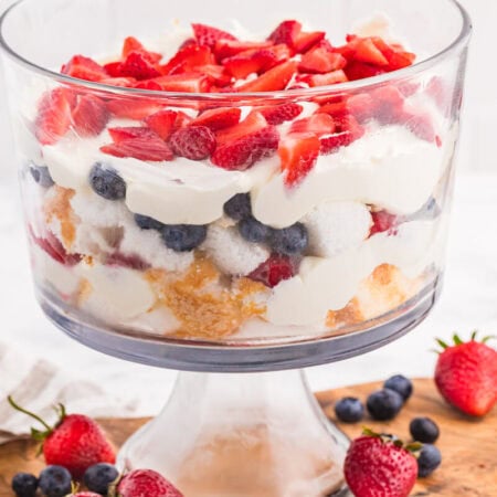 Angel Food Cake Trifle layered with fluffy cake, creamy vanilla filling, strawberries, blueberries, and raspberries in a clear glass trifle bowl.