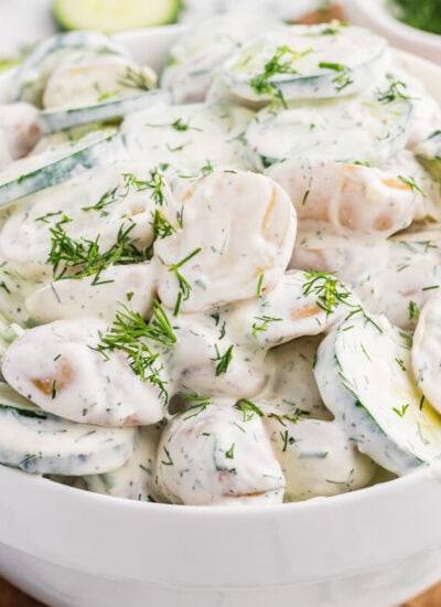 Creamy cucumber potato salad with baby potatoes, sliced cucumber, and fresh dill in a white serving bowl.