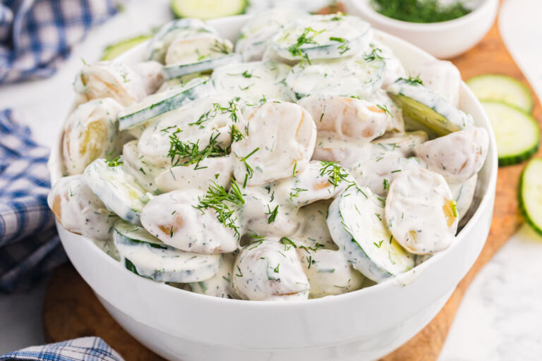 Creamy cucumber potato salad with baby potatoes, sliced cucumber, and fresh dill in a white serving bowl.