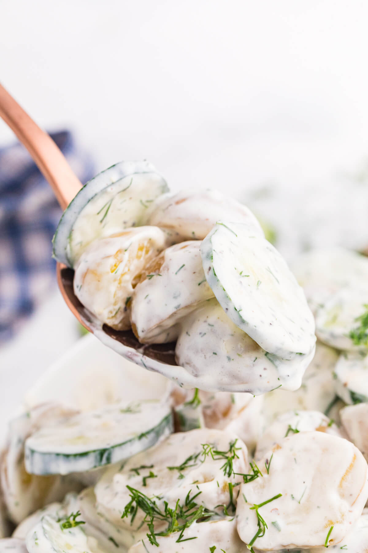 Spoonful of creamy cucumber potato salad with baby potatoes, cucumber slices, and fresh dill.