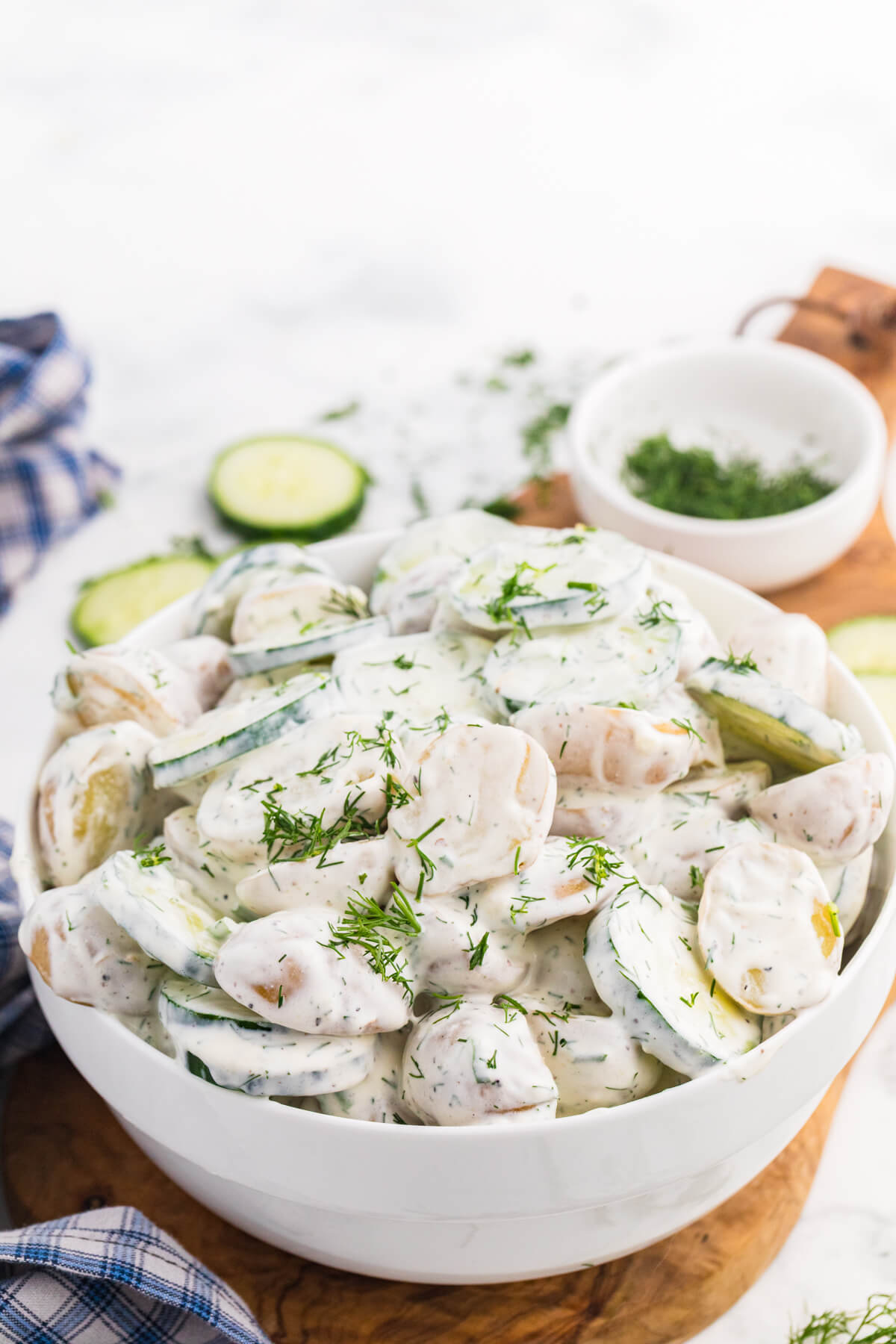 Creamy cucumber potato salad with baby potatoes, sliced cucumber, and fresh dill served in a white bowl.