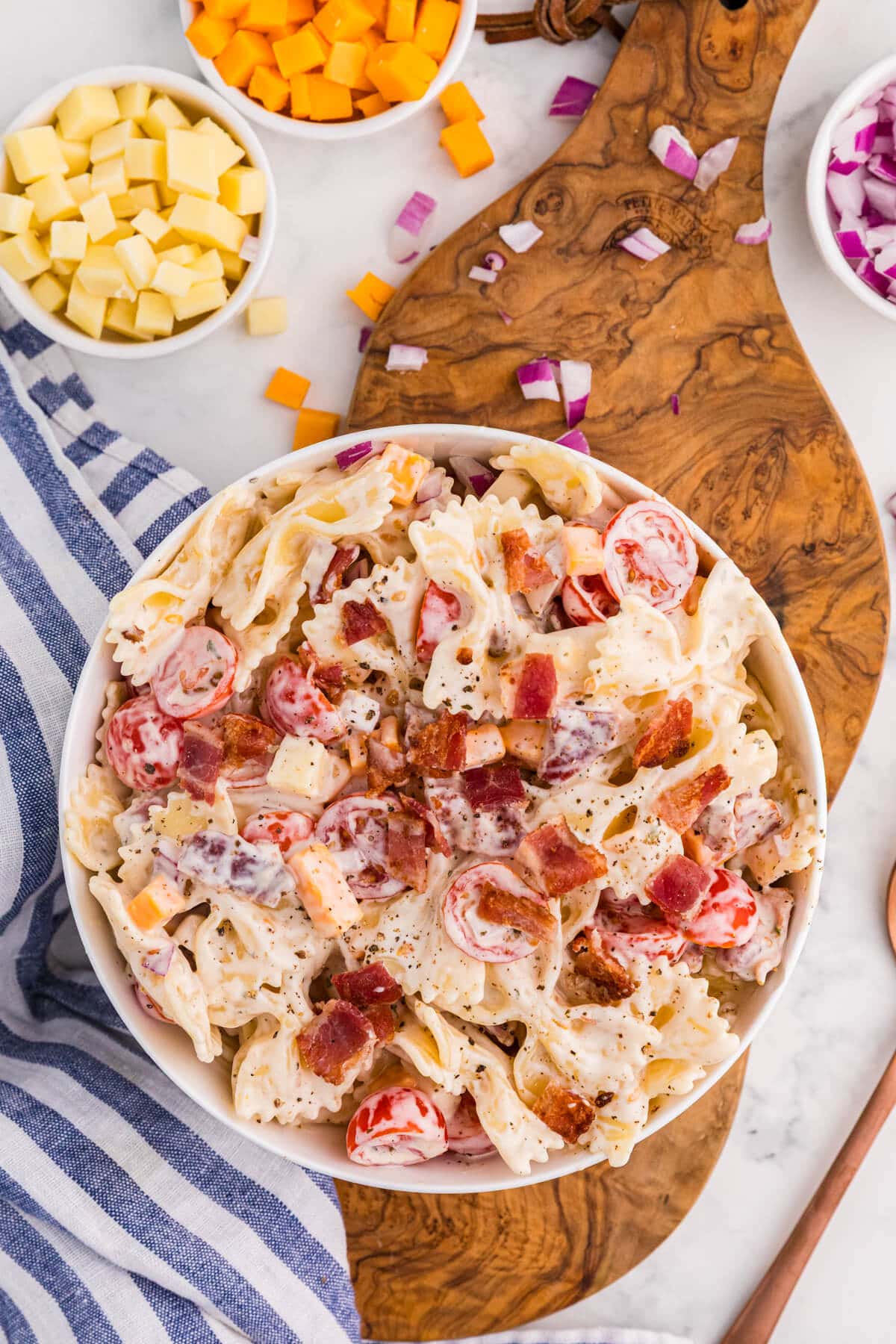 Overhead view of Million Dollar Pasta Salad with bowtie pasta, bacon, cheddar, mozzarella, cherry tomatoes, and red onion in a creamy ranch dressing.