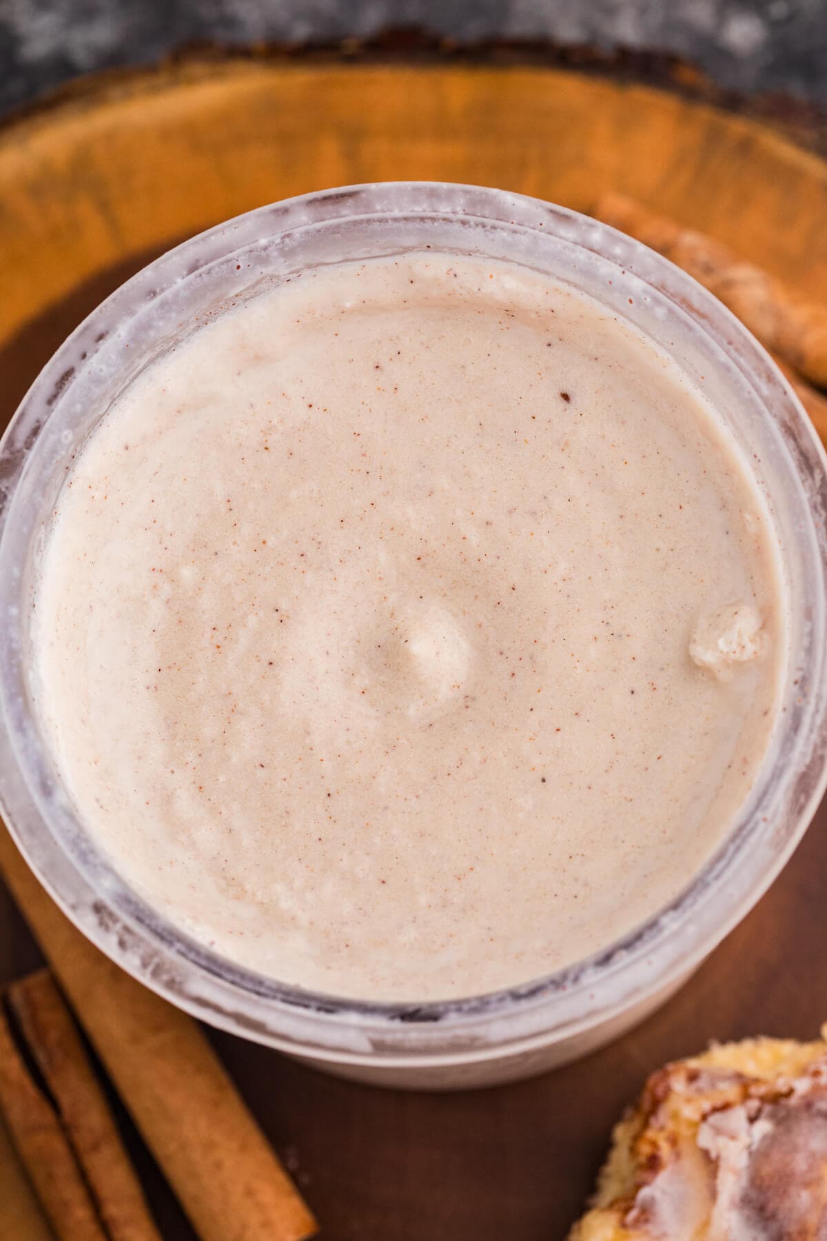 Close-up of creamy cinnamon roll ice cream in a Ninja CREAMi pint with cinnamon specks throughout.