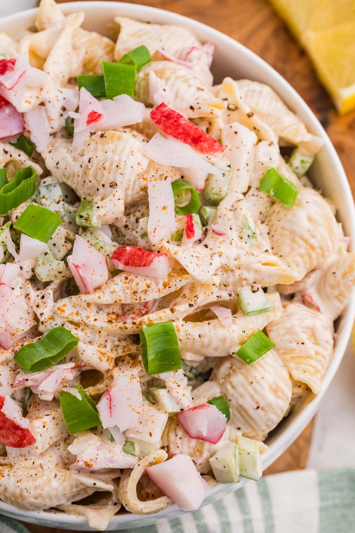 Close-up of creamy crab pasta salad with imitation crab, shell pasta, celery, green onions, and Old Bay seasoning.