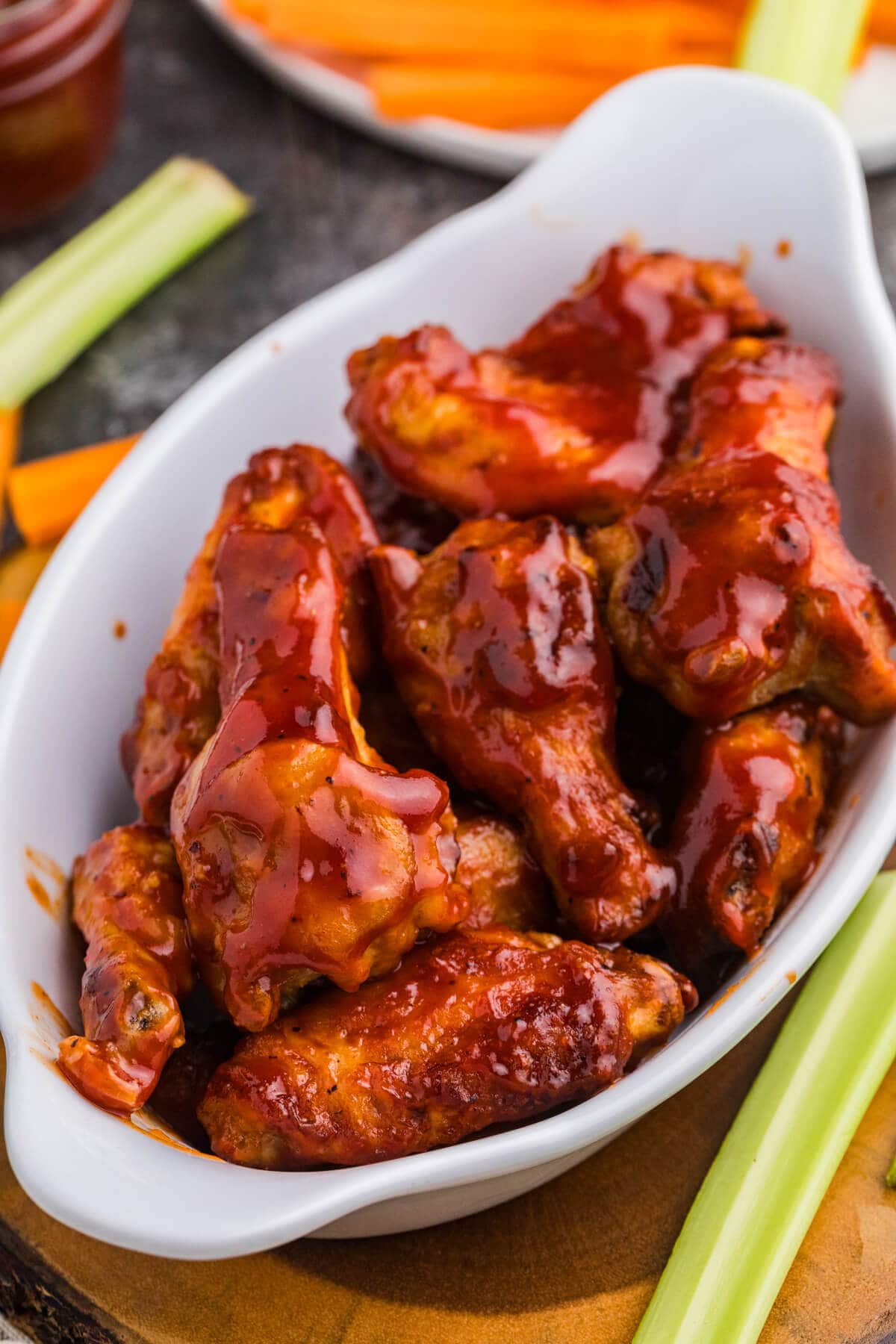 Chicken wings coated in glossy Honey Sriracha BBQ Sauce served with celery and carrot sticks.