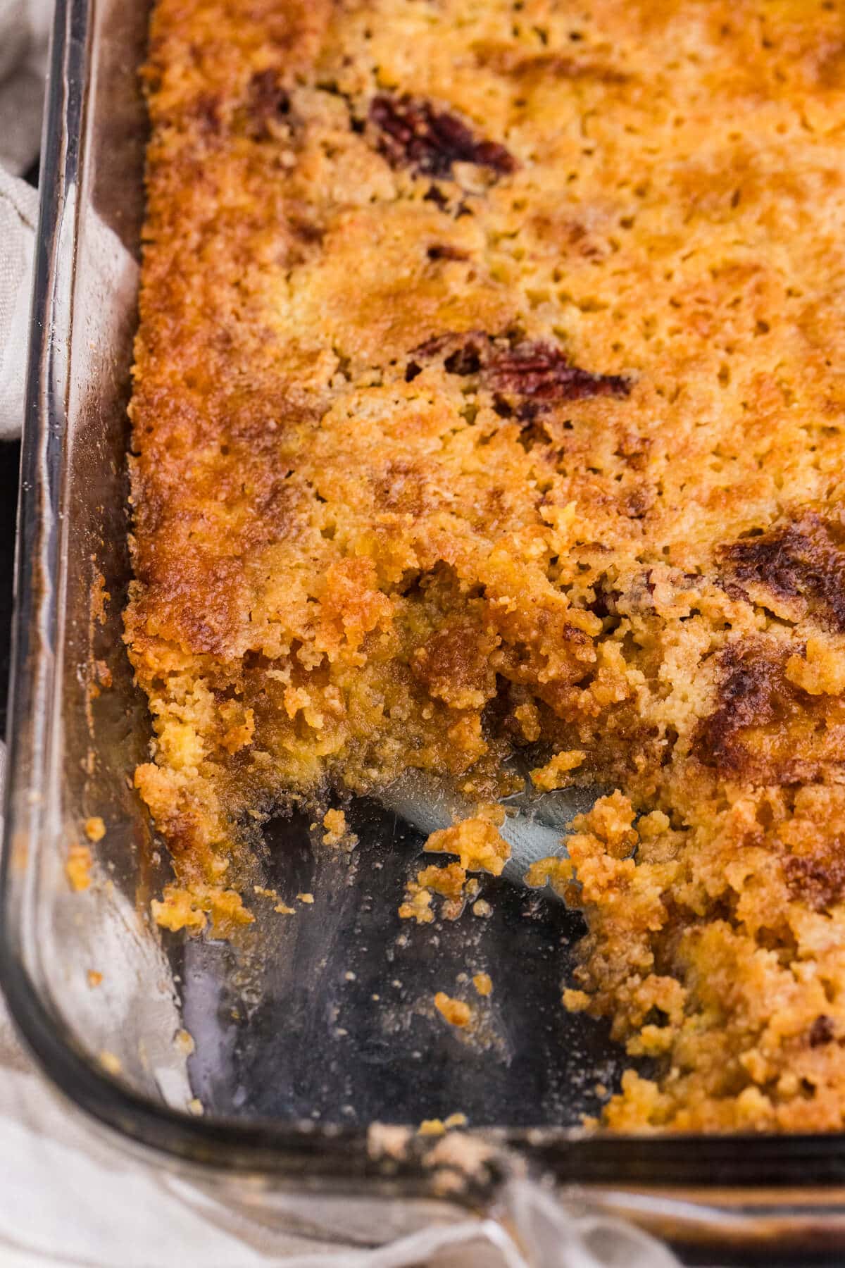 Maple Syrup Dump Cake in a baking dish showing the golden topping, pecans, and gooey maple filling underneath.