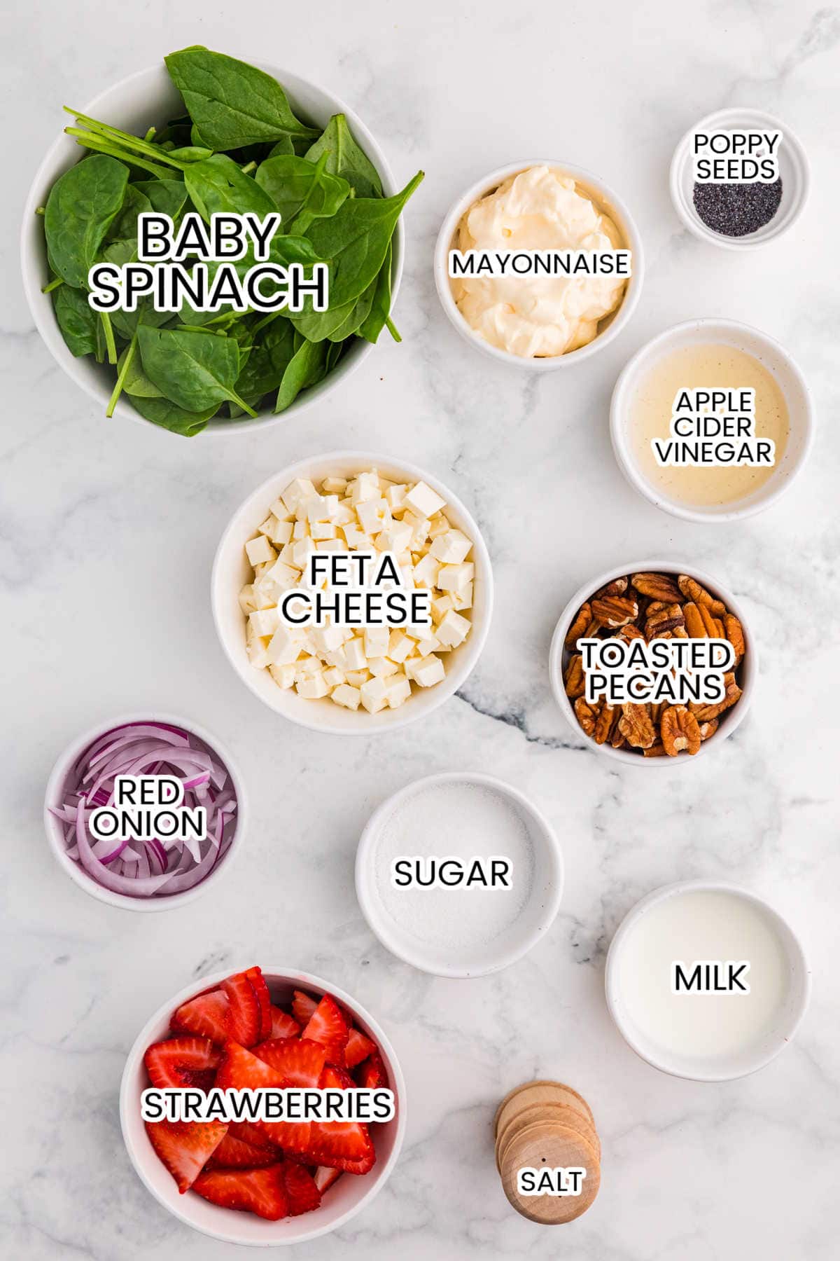 Ingredients for strawberry spinach salad including baby spinach, strawberries, feta cheese, toasted pecans, red onion, mayonnaise, milk, sugar, apple cider vinegar, poppy seeds, and salt.
