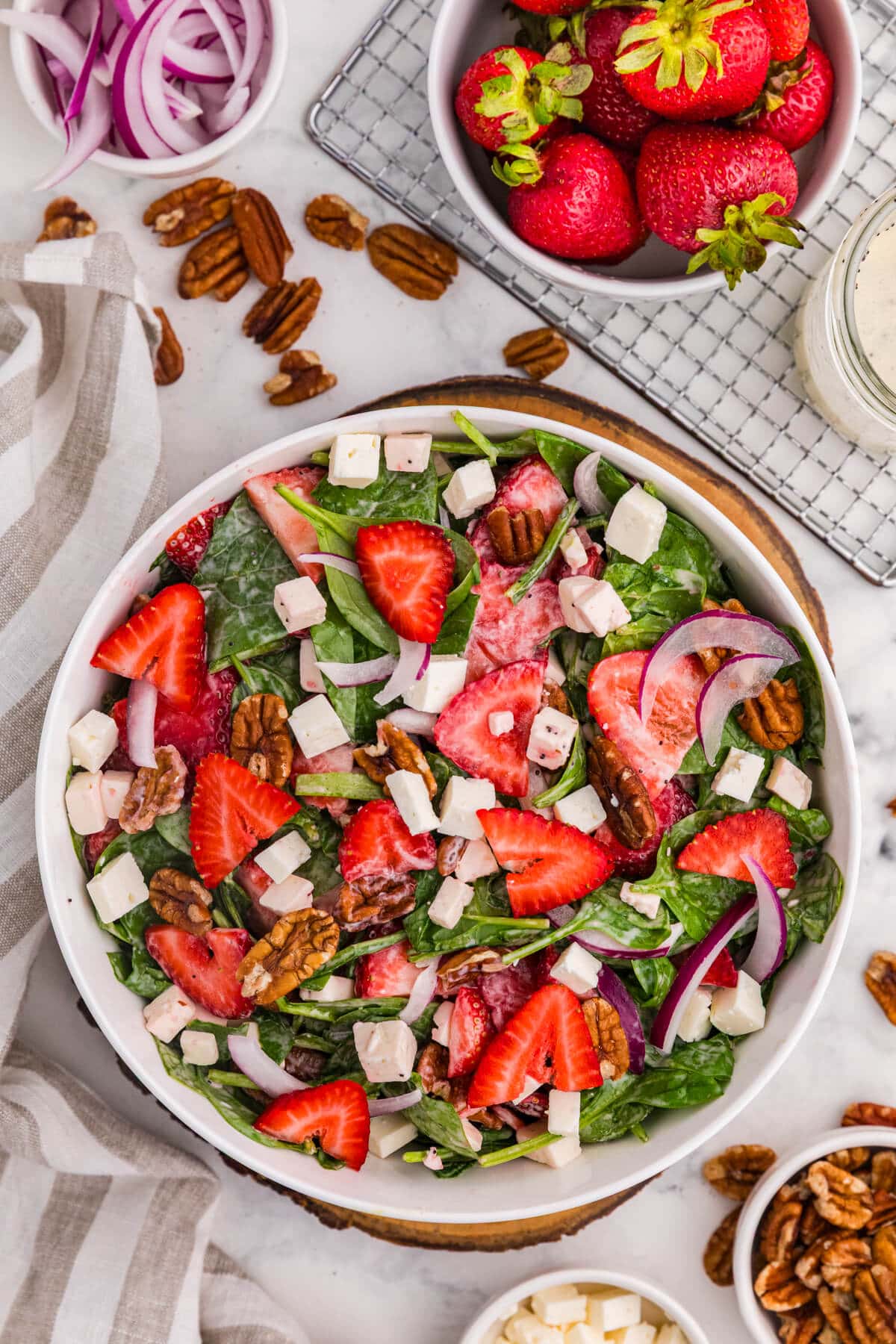 Strawberry spinach salad with fresh strawberries, feta cheese, toasted pecans, red onion, and creamy poppyseed dressing.