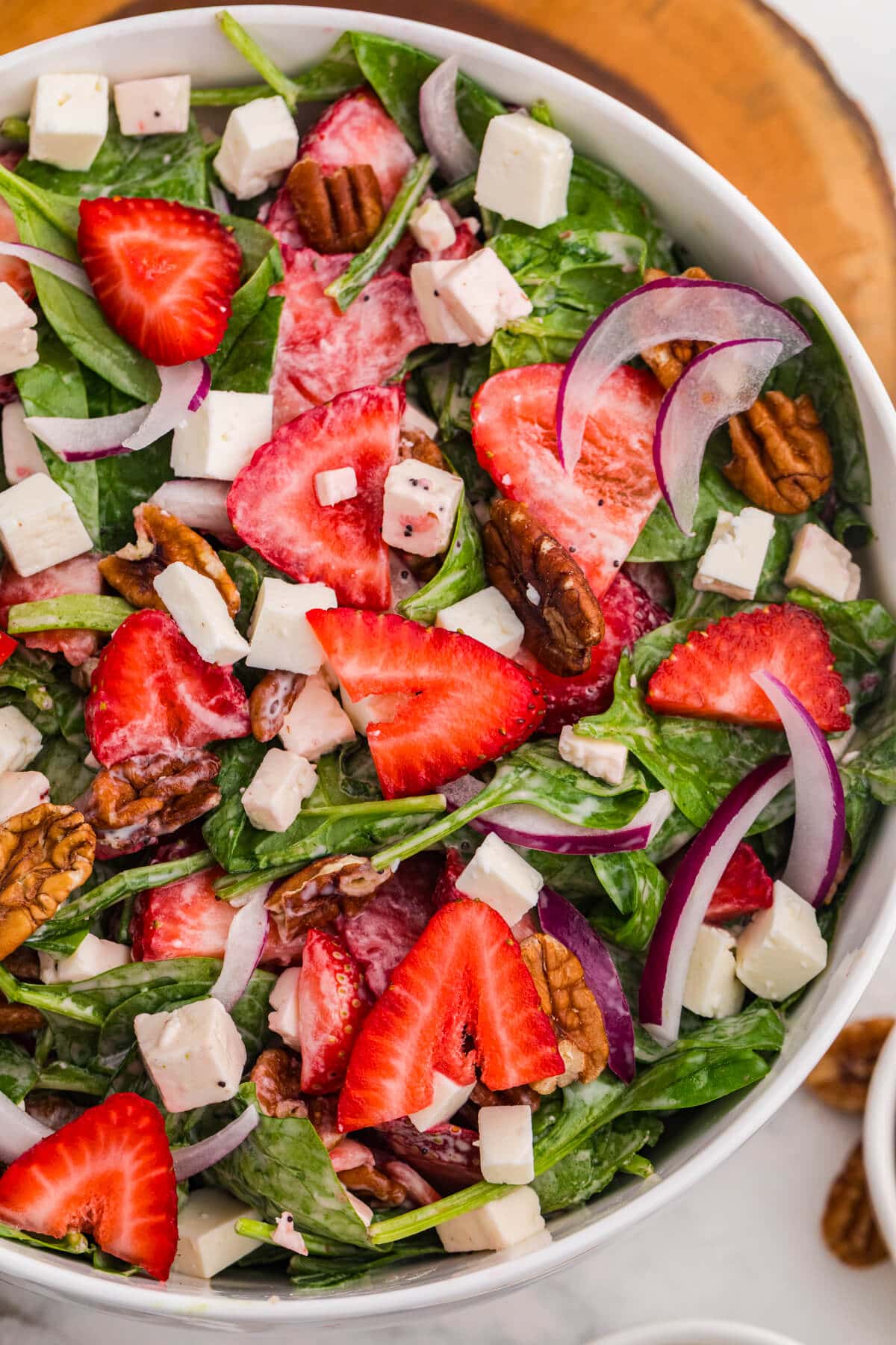 Close-up of strawberry spinach salad with fresh strawberries, feta cheese, toasted pecans, red onion, and creamy poppyseed dressing.