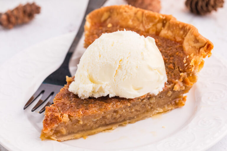 Slice of Maple Syrup Pie topped with a scoop of vanilla ice cream on a white plate.