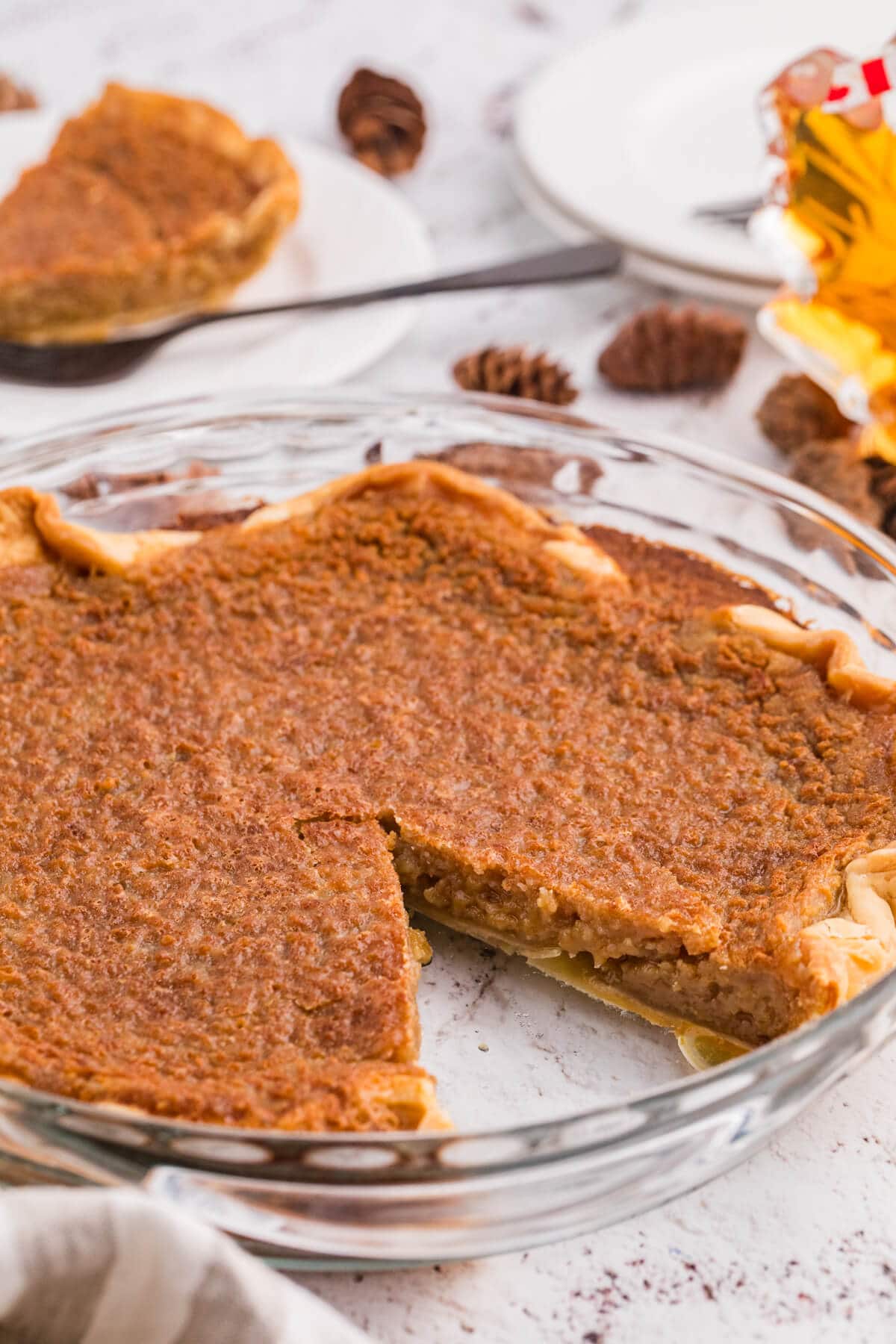 Whole Maple Syrup Pie in a glass pie plate with one slice removed, showing the gooey maple filling and flaky crust.