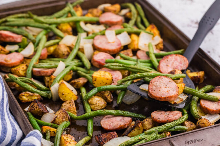 Sheet pan sausage, potatoes and green beans with browned kielbasa, roasted baby potatoes, green beans, and onion being served from the pan.